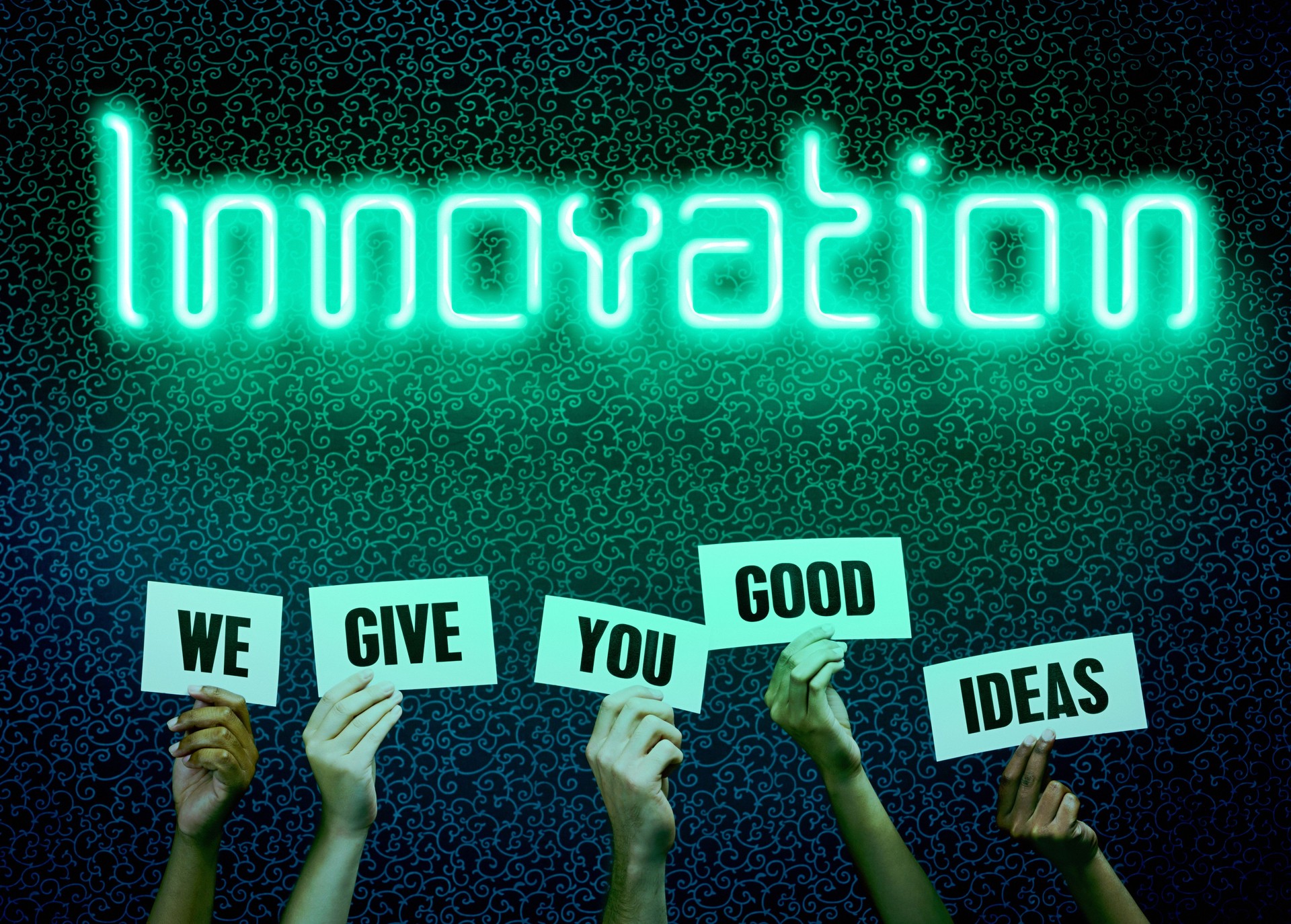 Innovation, reads glowing neon sign above group of people's hands holding signs reading We Give You Good Ideas